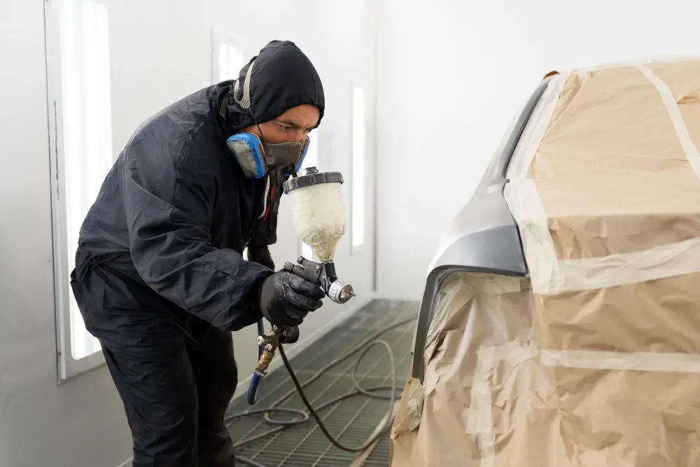 Mecanico con traje negro pintando coche